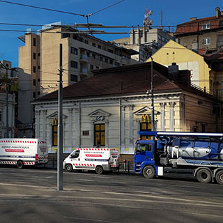 Vozila Poslova Grada na ulici ispred gradskih zgrada i tramvajskih vodova.